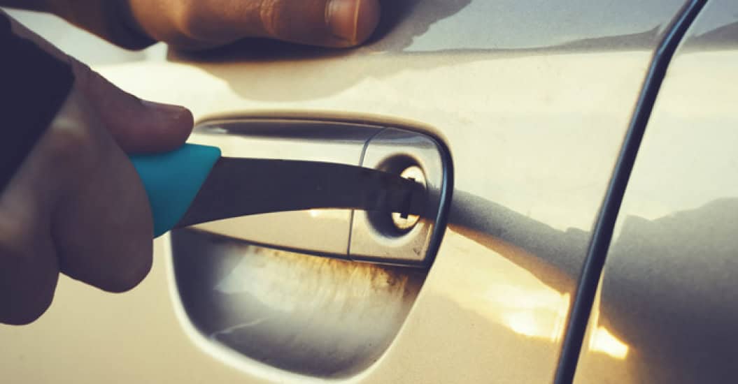 Thief using a sharp knife in a car key lock to break in