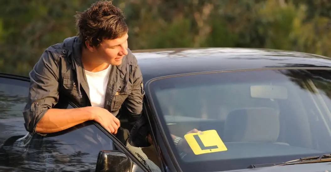 Young male driver putting his L plates in his car windscreen