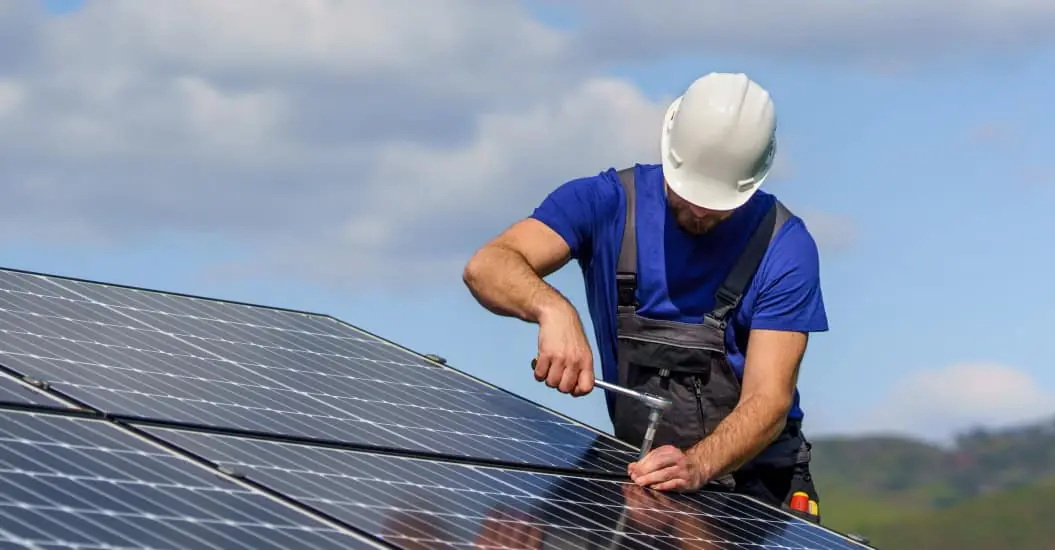 Tradesman installing solar panels on house roof