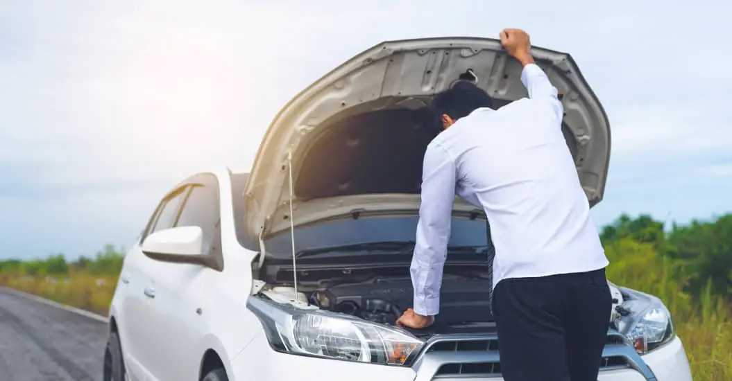 Man looking under the bonnet of his broken down car