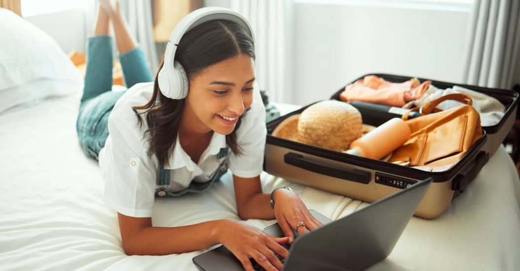 Young woman using her laptop while packing for a holiday