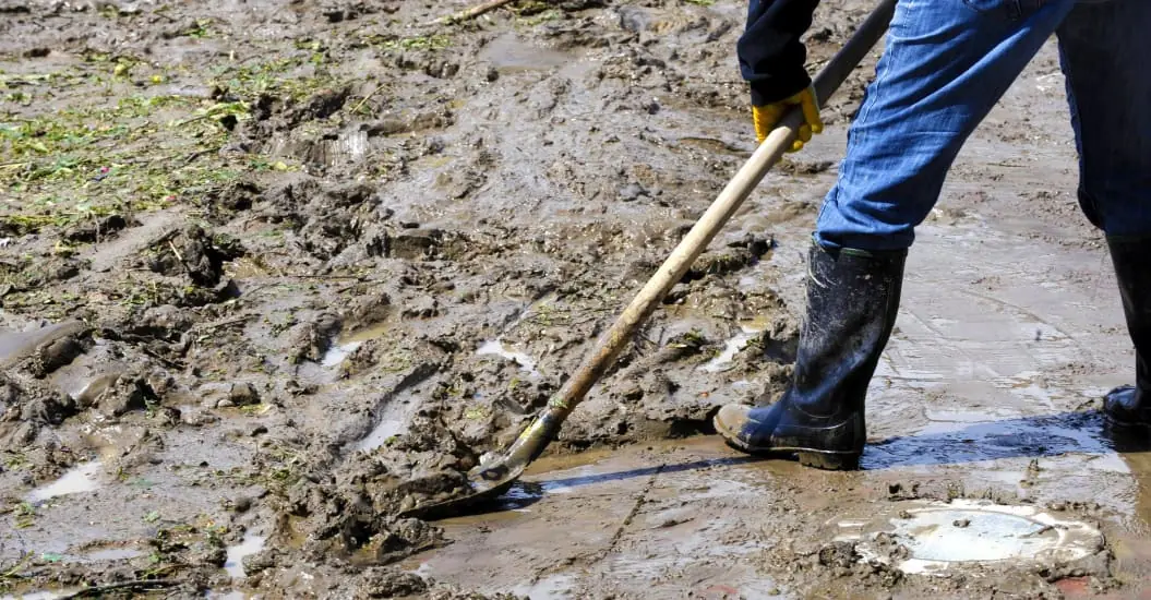 Man cleaning up mud deluge after a storm