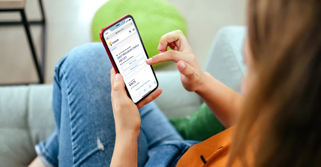 Woman using smartphone to review insurance policy renewal options while sitting on couch