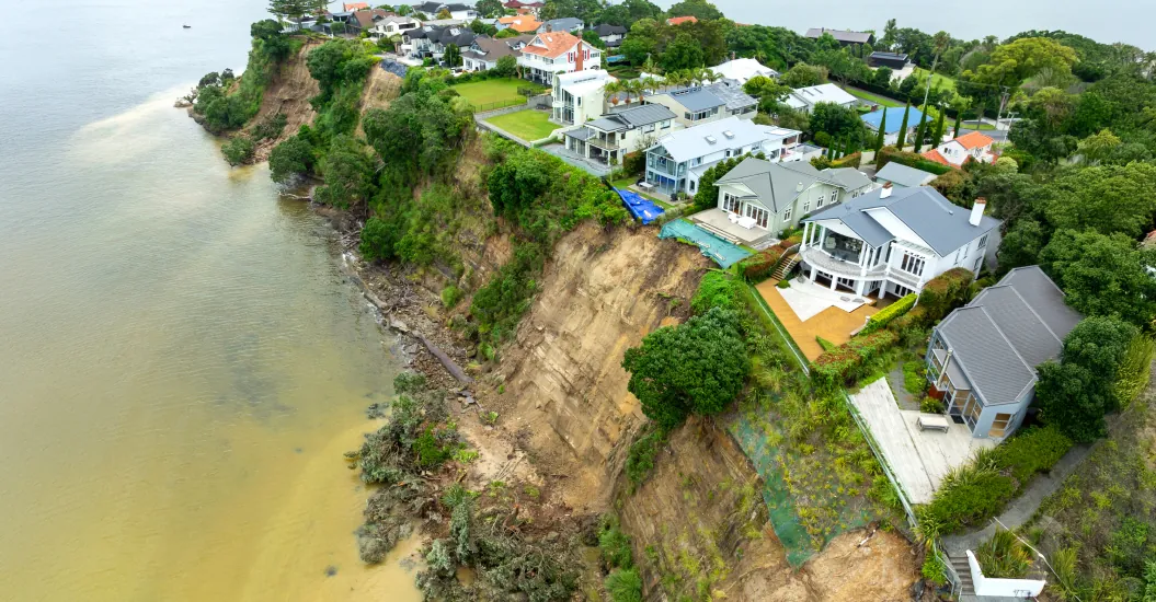 Aerial view of cliff front homes with a large landslide threatening collapse along the shoreline