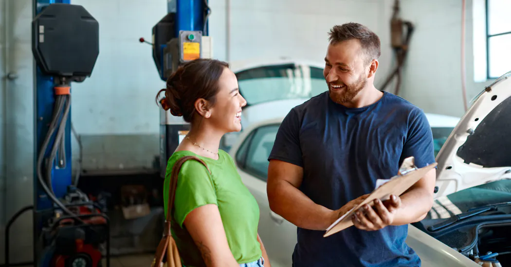 woman consults with friendly mechanic holding clipboard