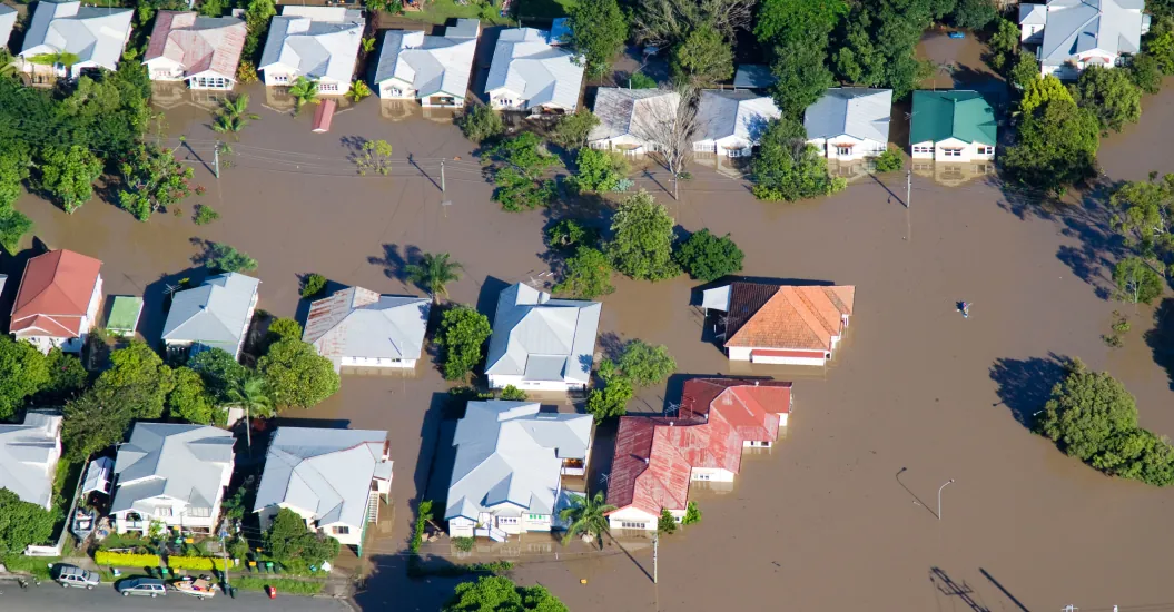 Aerial view of a flooded residential neighborhood showing houses partially submerged in brown floodwater.