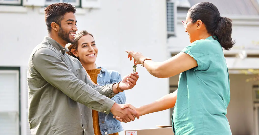 A landlord handing over house keys to a couple of renters