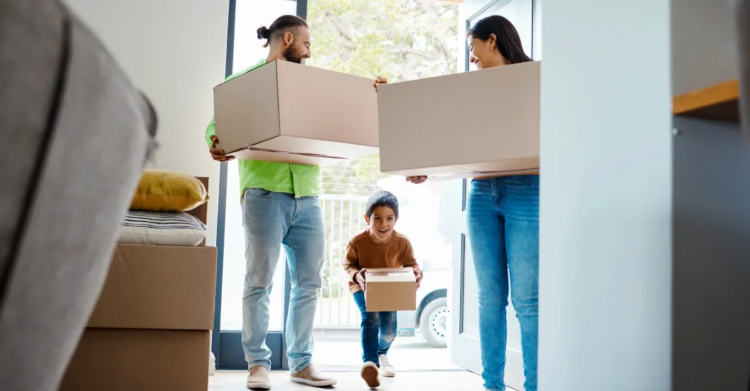 An excited family excitedly move boxes of belongings into the new home they have bought as first-home buyers.